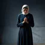 A solitary adult figure, fully clothed in modest, professional dress, stands in a subtly dim, enclosed space. Their posture is slightly slumped, conveying a sense of invisible weight or a heavy burden on their shoulders. A faint, almost translucent, dark mist or shadow seems to subtly cling around them, symbolizing the weight of past grudges. Their expression is thoughtful and slightly somber, yet resilient. The background is simple and uncluttered, emphasizing the figure. Natural body proportions, perfect anatomy, well-formed hands, correct proportions, natural pose. Family-friendly, safe for work, appropriate content, professional photography, high quality.